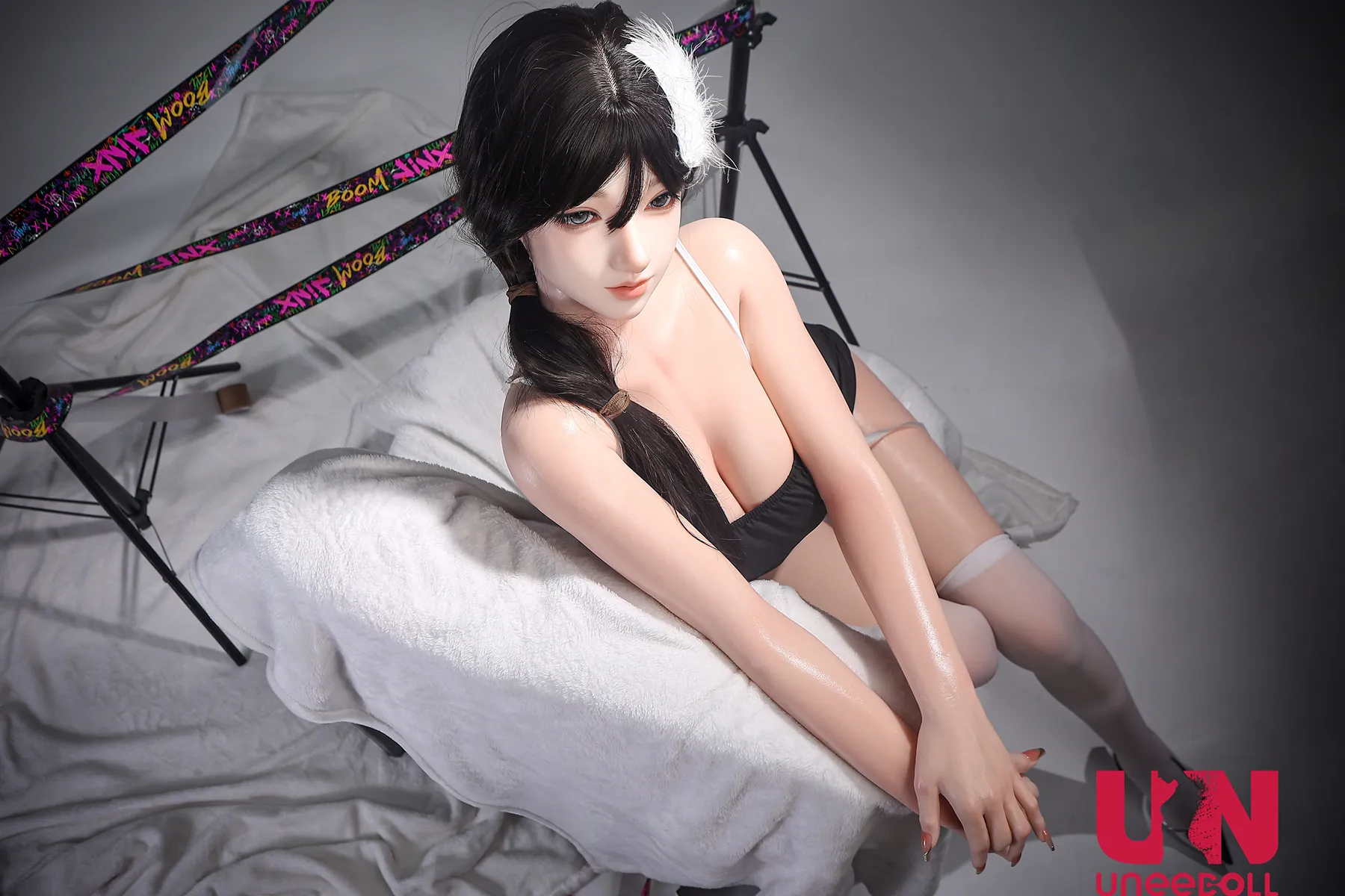 Aurora wears a short black dress and white stockings while sitting sideways on a white-draped studio chair